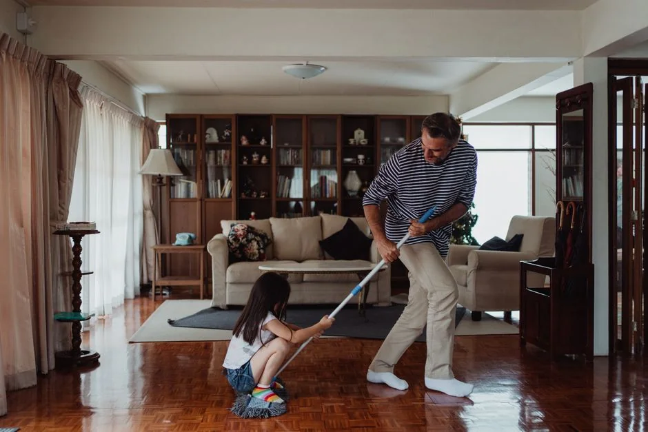 a-woman-in-a-green-shirt-and-black-gloves-vacuuming-a-gray-ottoman-5txz228u4eo